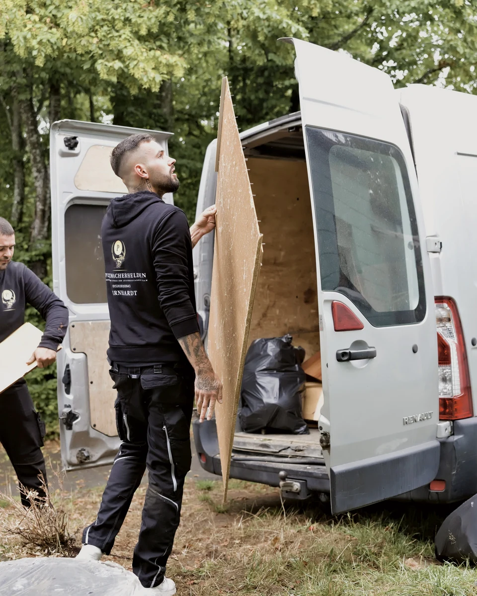 Ein Mitarbeiter der Platzmacherhelden verlädt eine Möbelplatte in den Transporter