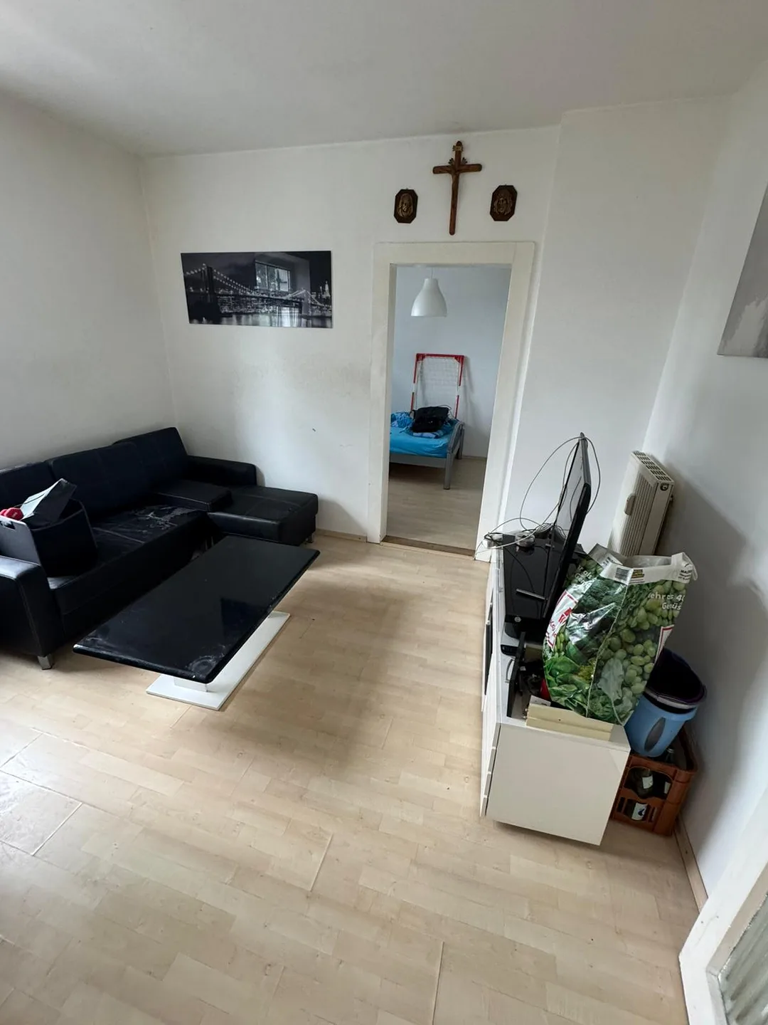 Wohnzimmer nach der Entrümpelung: freier Boden, Sofa und Couchtisch, Blick ins aufgeräumte Schlafzimmer